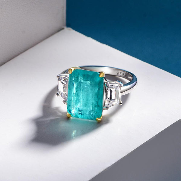 4 carat Paraiba blue three-stone ring in sterling silver and gold with an ocean-inspired design, ideal for engagements.