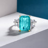 4 carat Paraiba blue three-stone ring in sterling silver and gold with an ocean-inspired design, ideal for engagements.