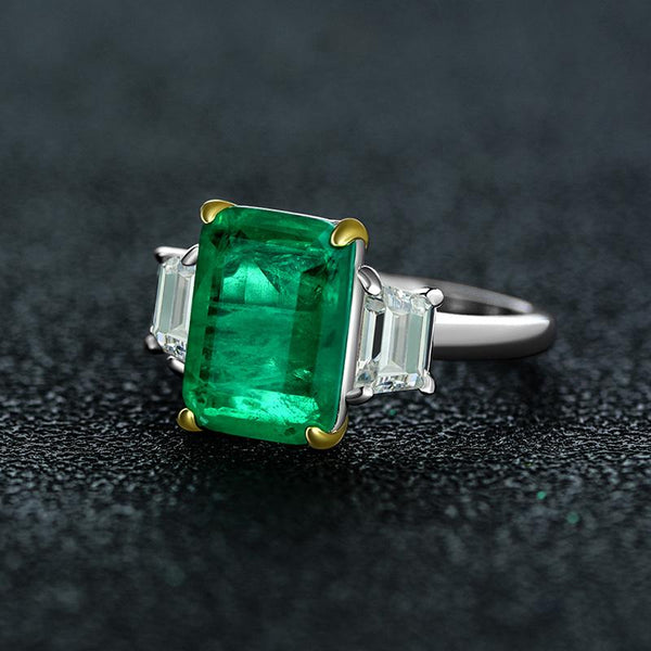 Green Emerald Halo Ring with vivid emerald cut stone, surrounded by a sparkling three stone, perfect for engagements and anniversary