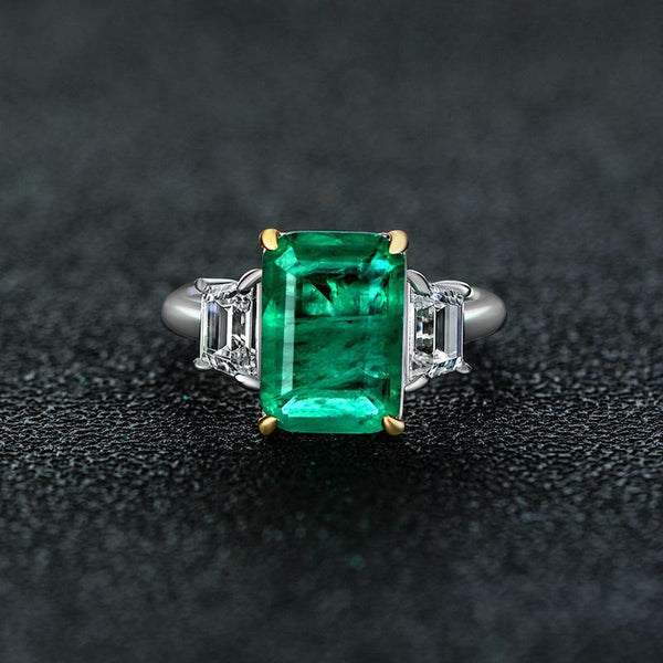 Green Emerald Halo Ring with vivid emerald cut stone, surrounded by a sparkling three stone, perfect for engagements and anniversary