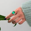 Green Emerald Halo Ring with vivid emerald cut stone, surrounded by a sparkling three stone, perfect for engagements and anniversary